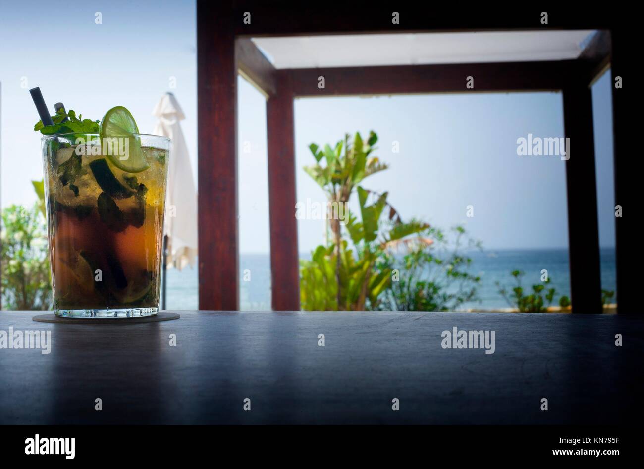 Il Mojito drink sulla barra di legno con poltrona letto e Spiaggia di sfocatura dello sfondo. Foto Stock