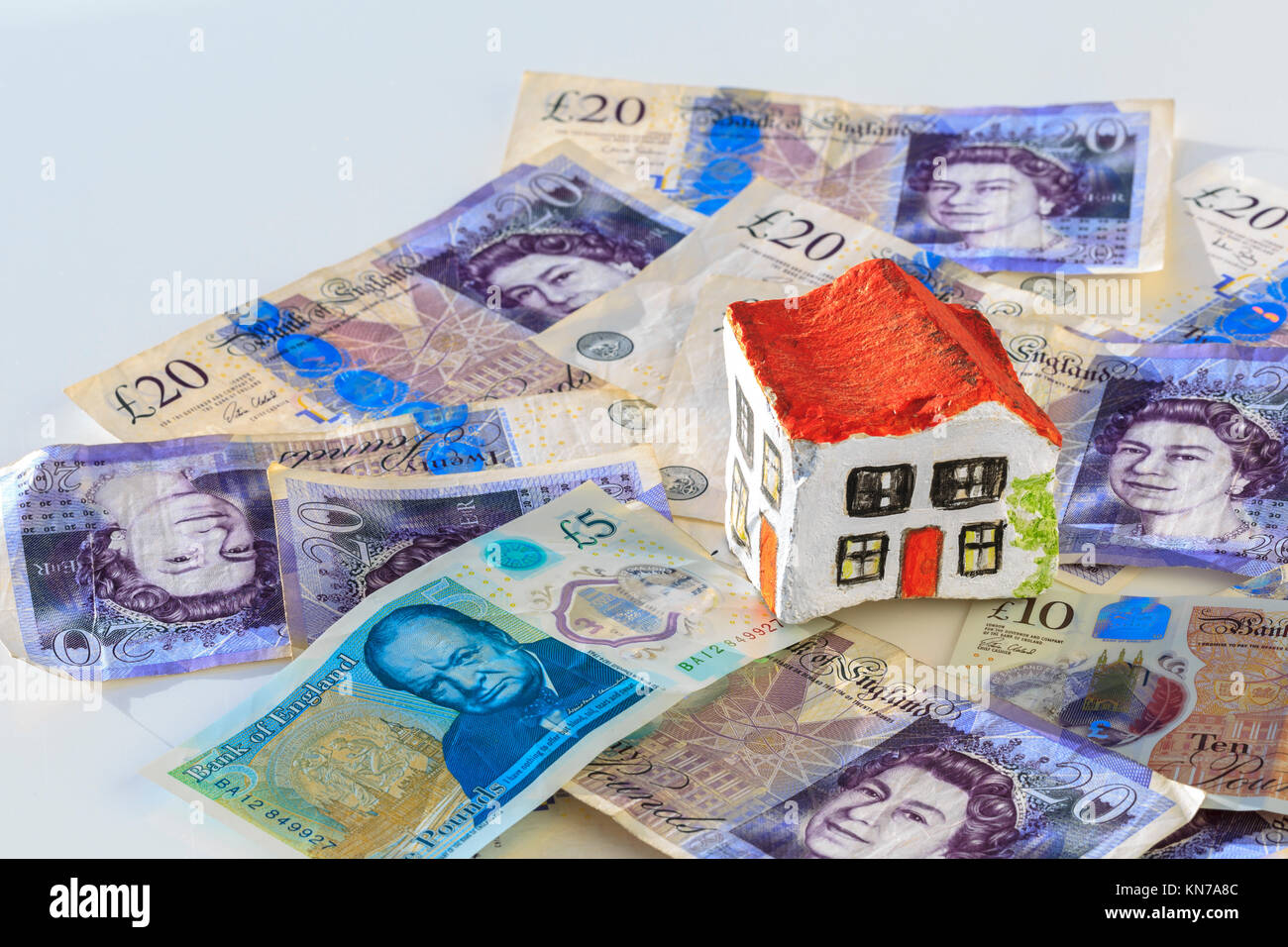Dipinto a mano casa di pietra seduti su venti pound note valuta britannica suggerendo un risparmio sui costi di bollo Foto Stock
