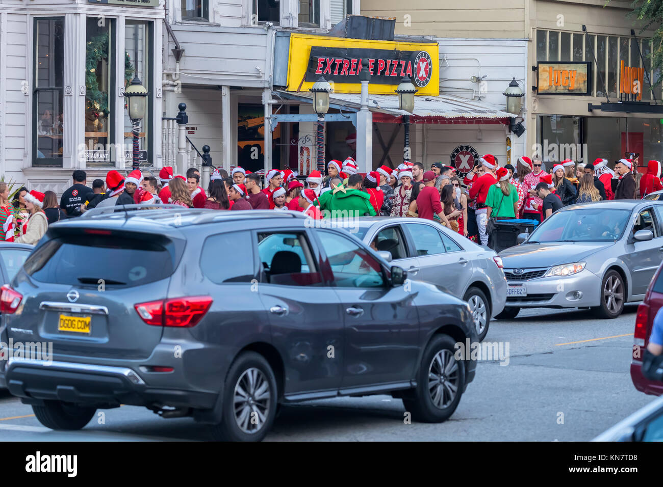 Giovani frequentatori di partito, vestiti da Babbo Natale , in attesa in fila per entrare in un bar per la Santa con la celebrazione in San Francisco, California, Stati Uniti. Foto Stock