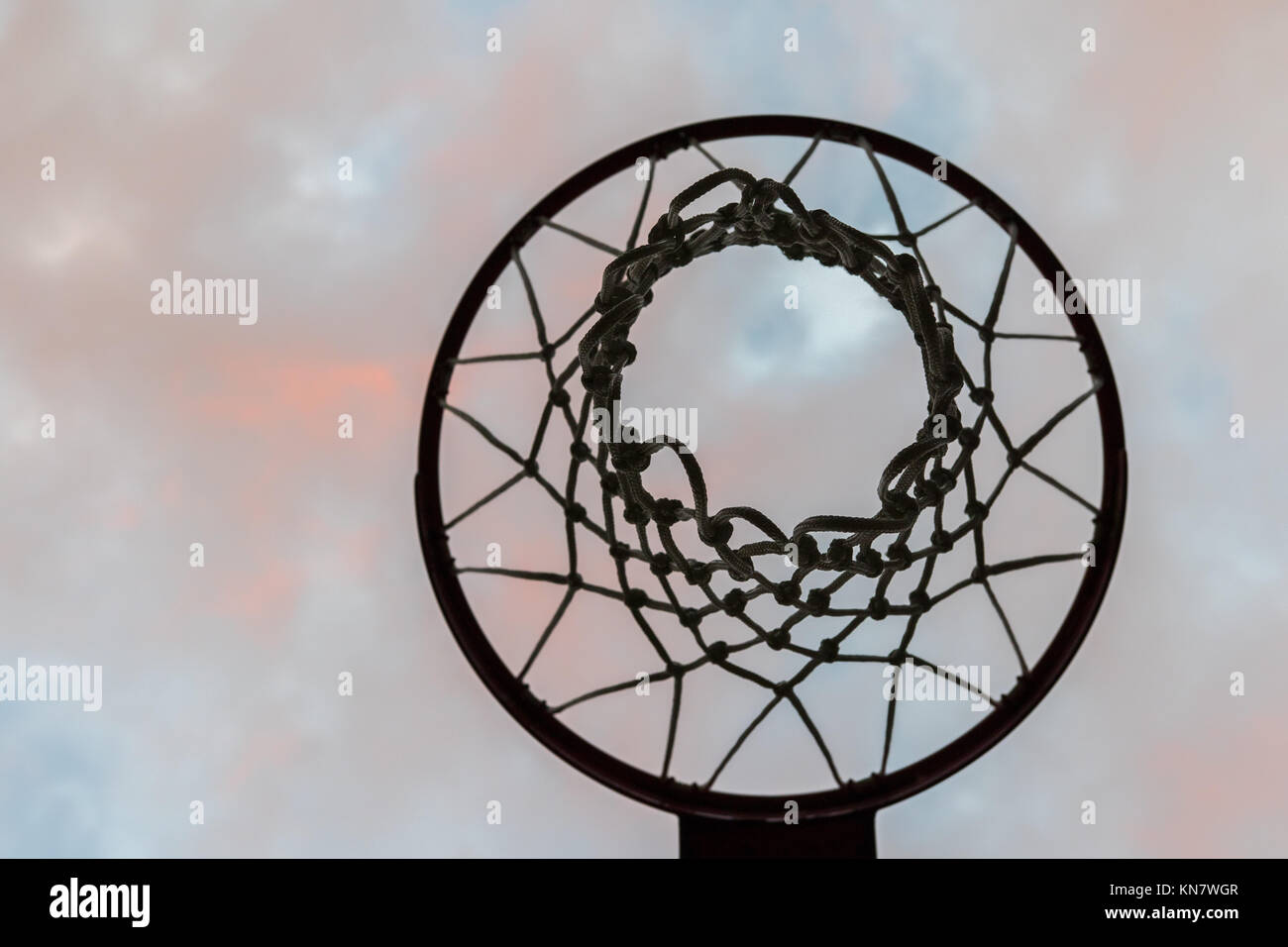 Guardando in alto attraverso una Basketball hoop con net in un cielo nuvoloso Foto Stock