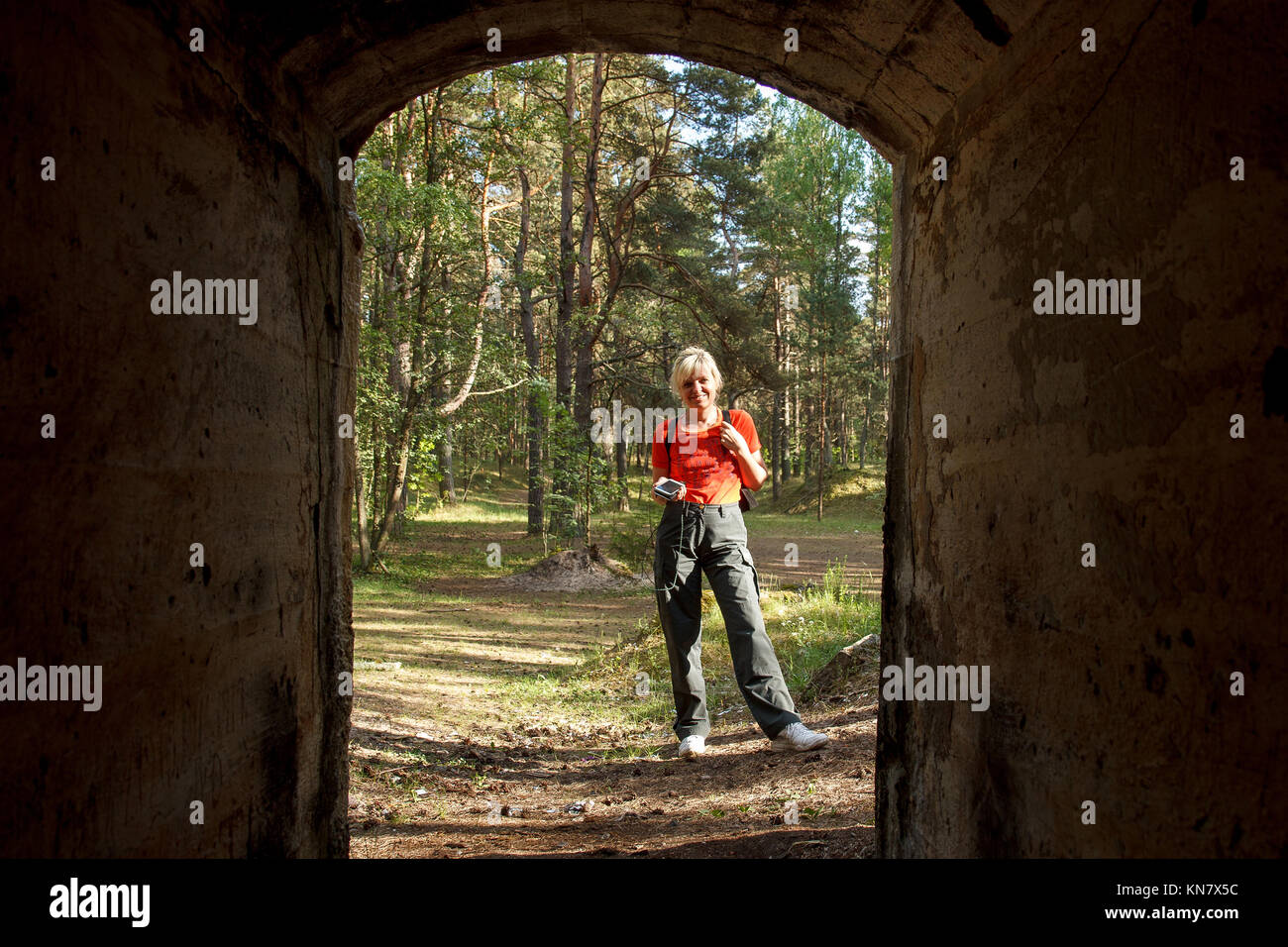 Donna che mantiene smartphone durante il geocaching in bunker abbandonati Foto Stock