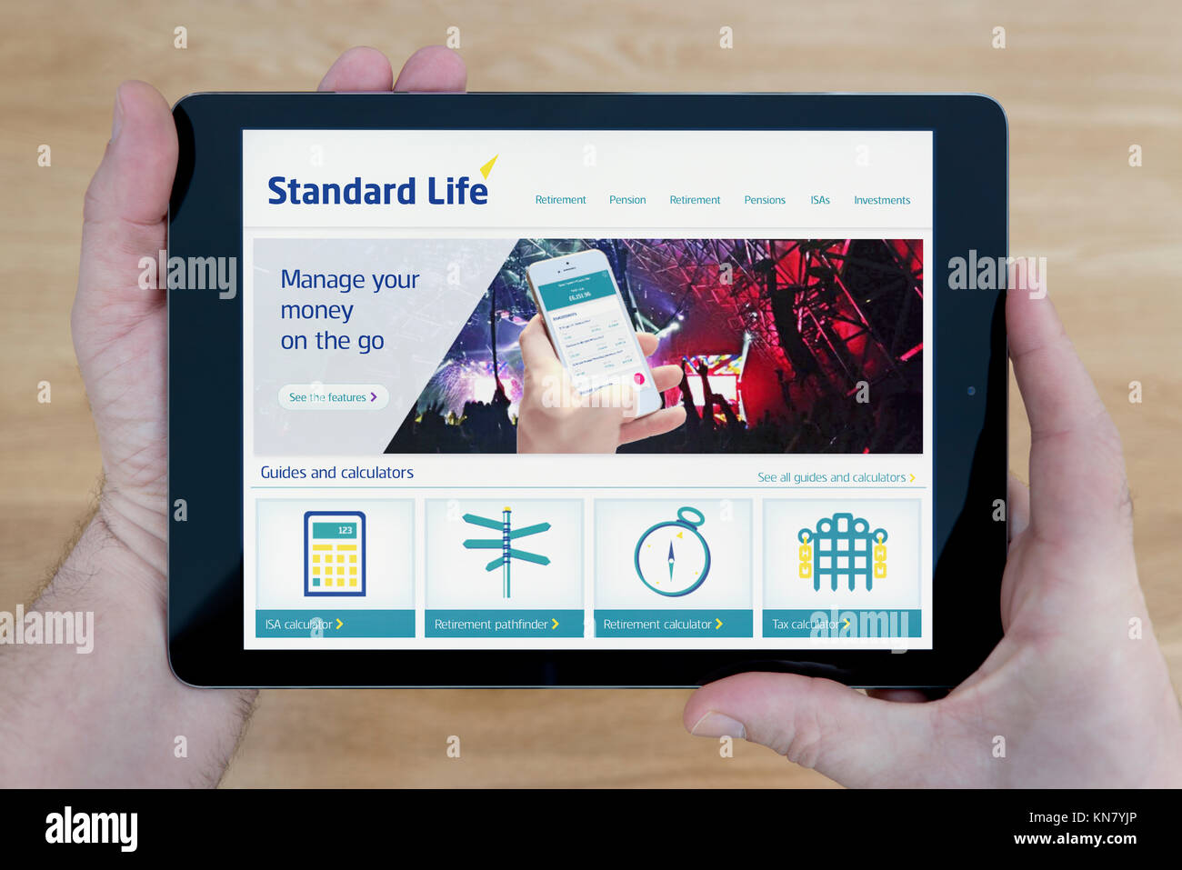 L'uomo guarda la Standard Life sito web sul suo iPad dispositivo tablet, sparato contro un tavolo di legno top sfondo (solo uso editoriale) Foto Stock