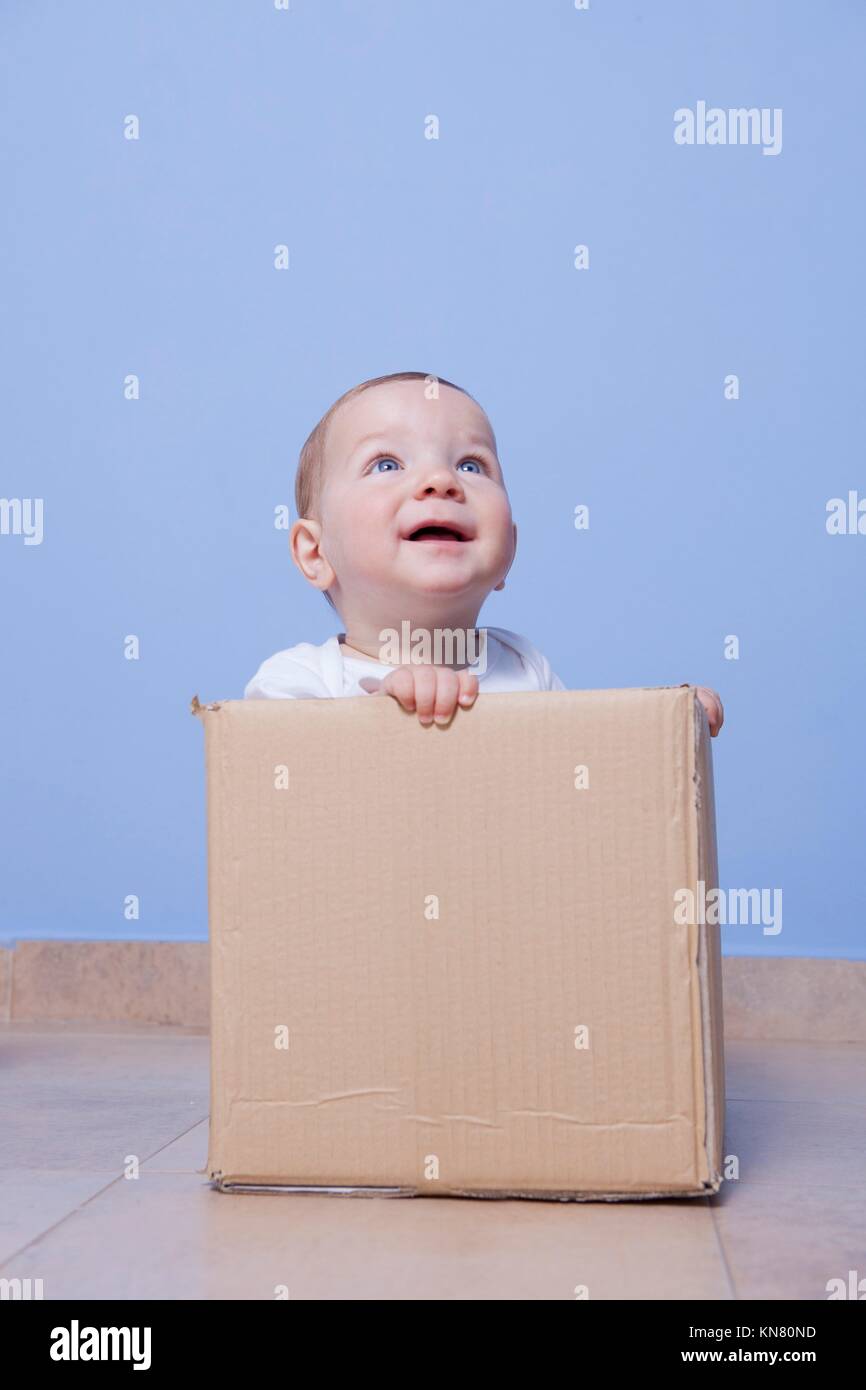 Ritratto di un simpatico baby giocando in un marrone scatola di cartone. Foto Stock