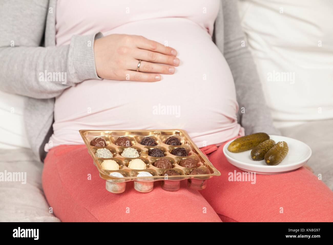 Donna incinta con il cetriolo aspro e caramelle. Foto Stock