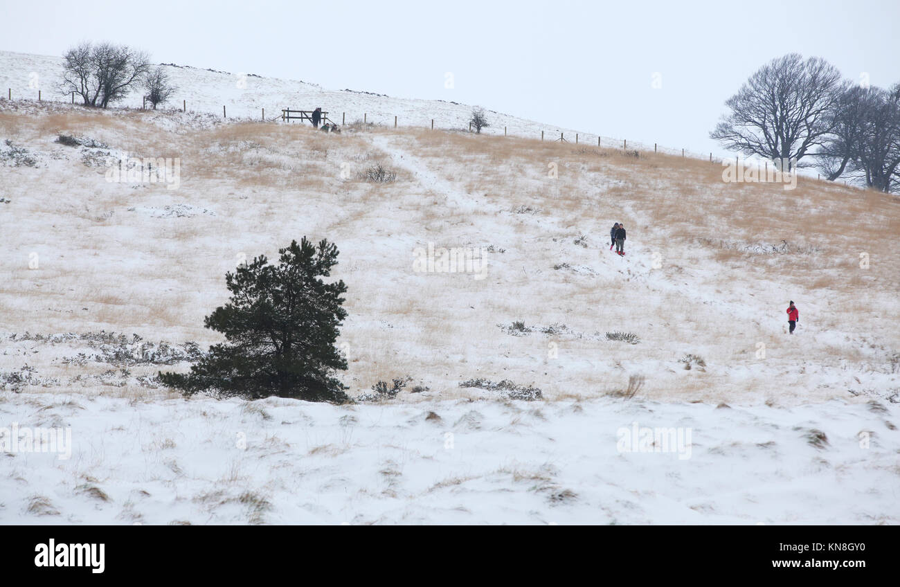 Persone che camminano giù coperta di neve collina a Stockhill boschi vicino Priddy in Somerset Foto Stock