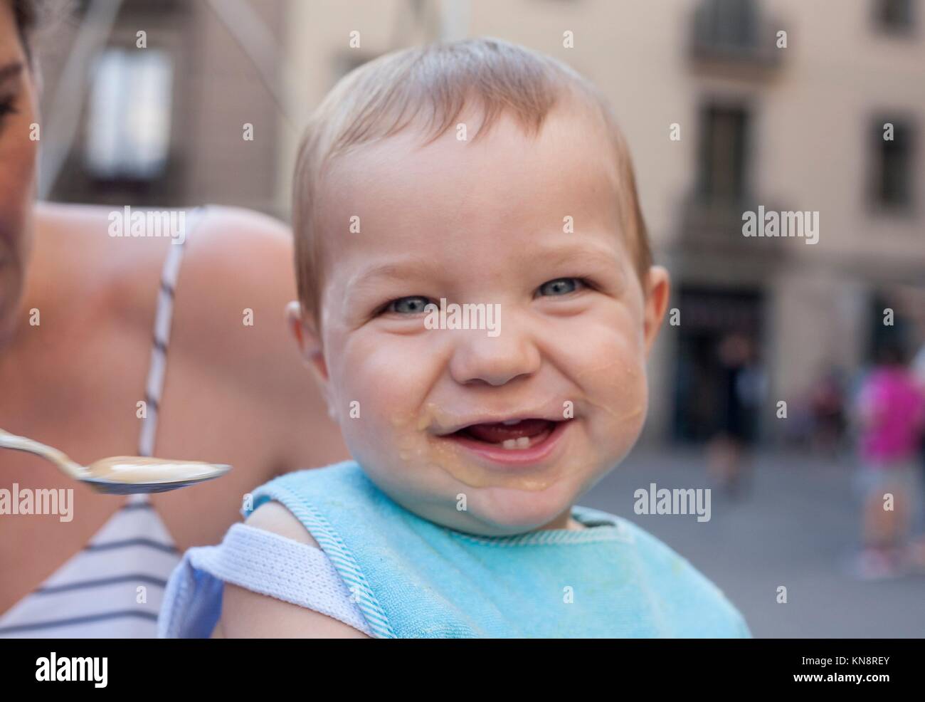 Madre che nutre il suo happy baby boy con frutta poltiglia all'esterno. Foto Stock