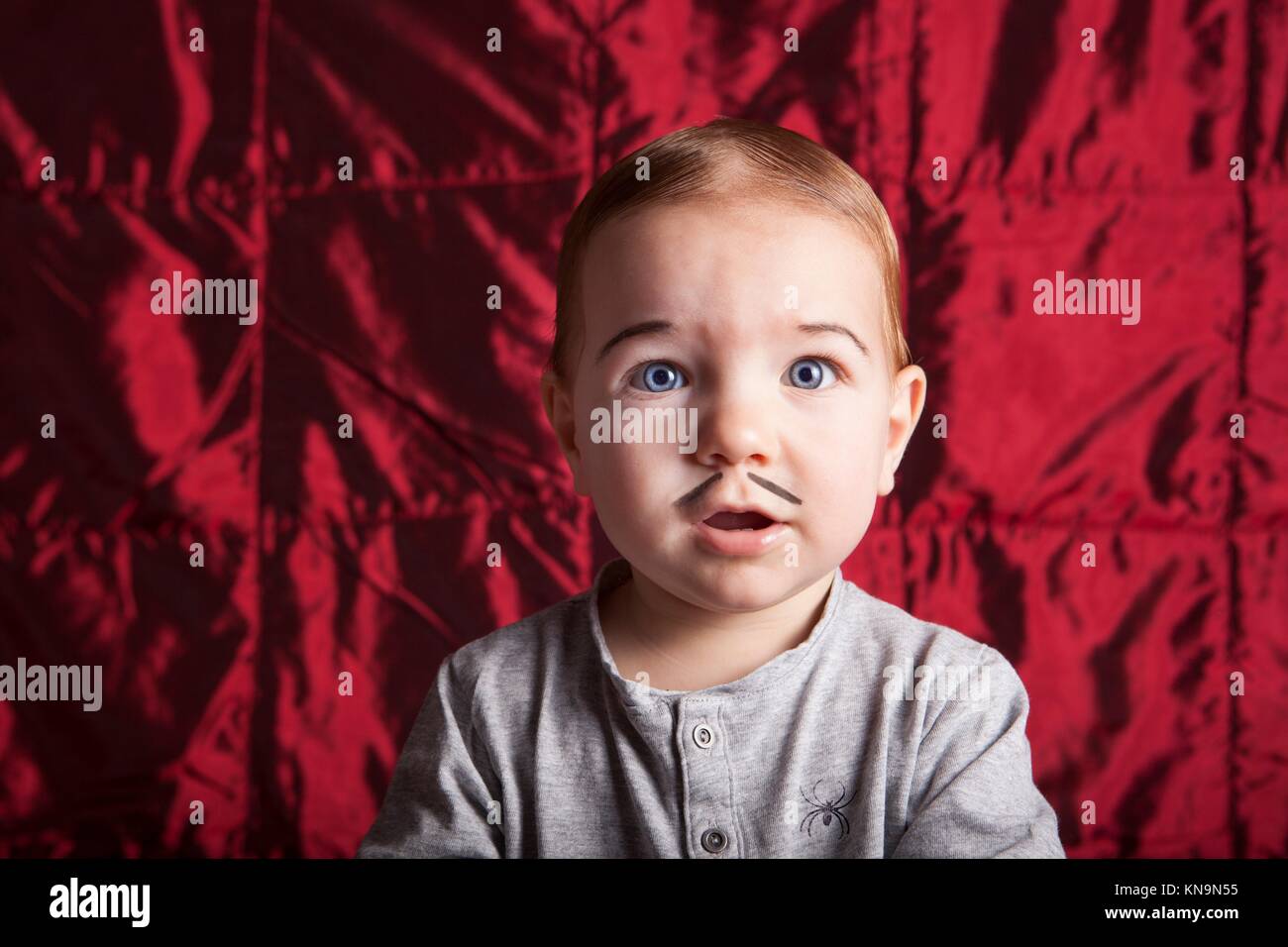 Ritratto di un ragazzino dress up per la festa di Halloween. Raso rosso sfondo. Foto Stock