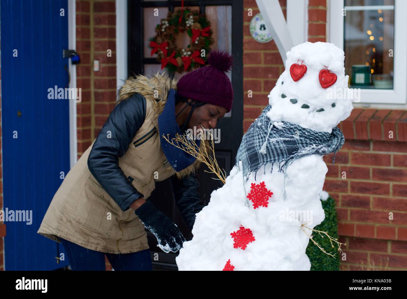 Donna costruire un pupazzo di neve a Hemel Hempstead, Hertfordshire, Regno Unito Foto Stock