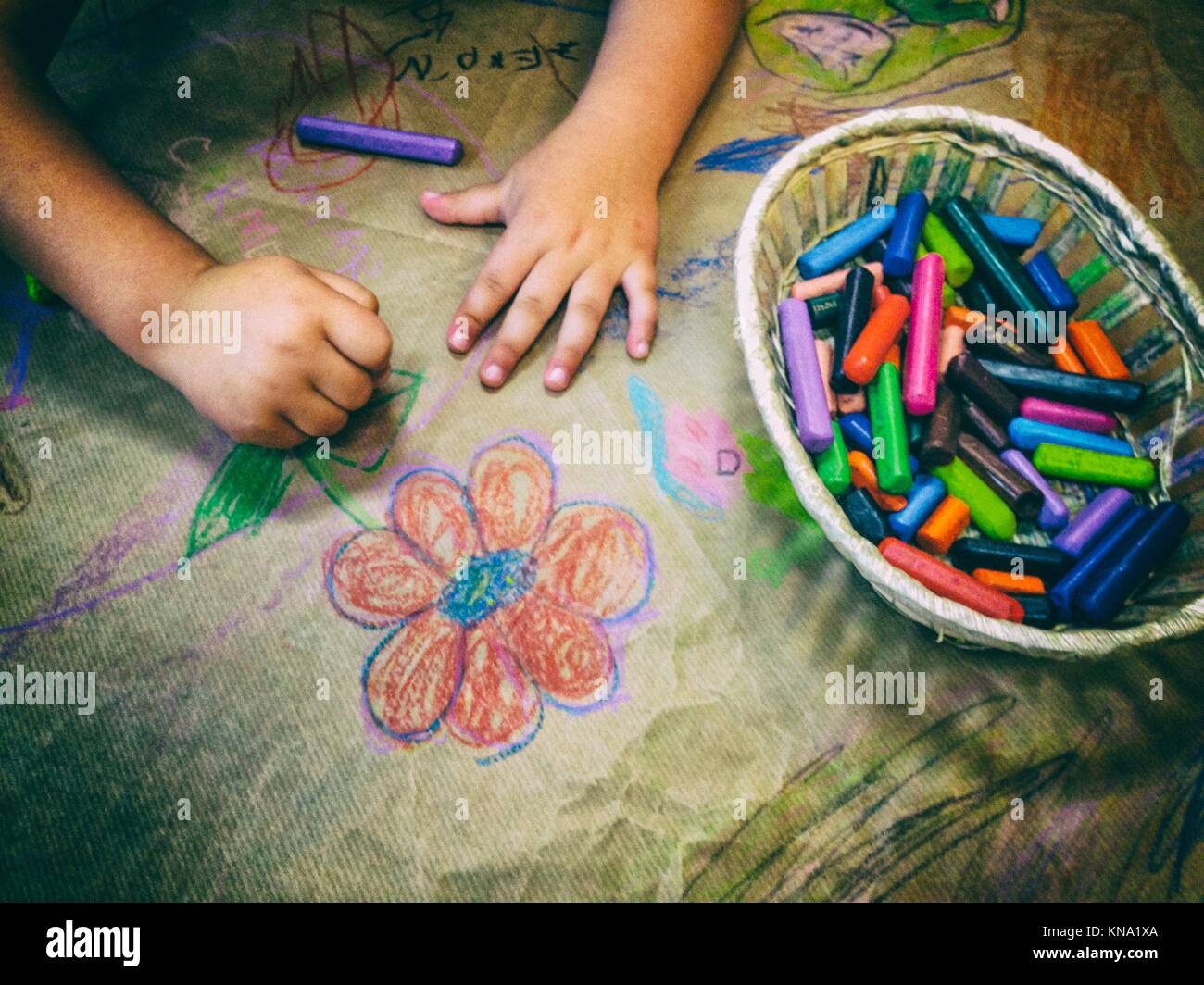 Disegno del bambino con un paniere di cera pastelli su imbarcazioni della carta da imballaggio. Angolo di Alta Vista. Foto Stock