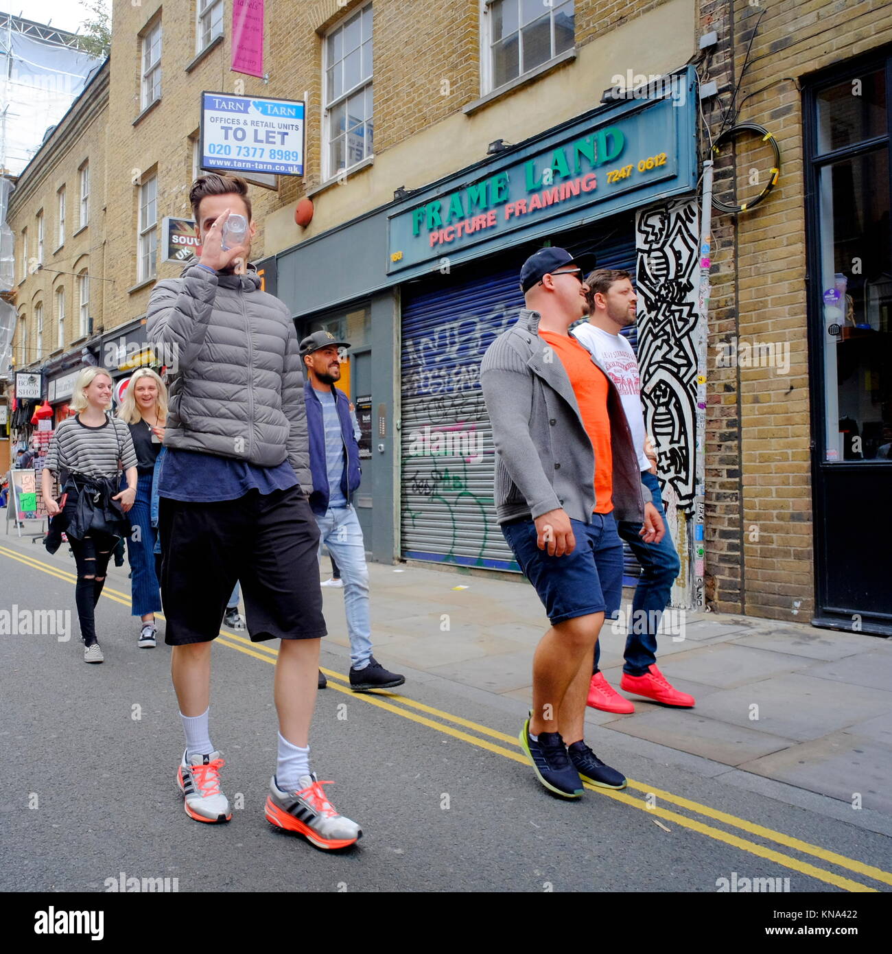 Un gruppo di uomini a piedi su Brick Lane in Shoreditch, London, England, Regno Unito Foto Stock