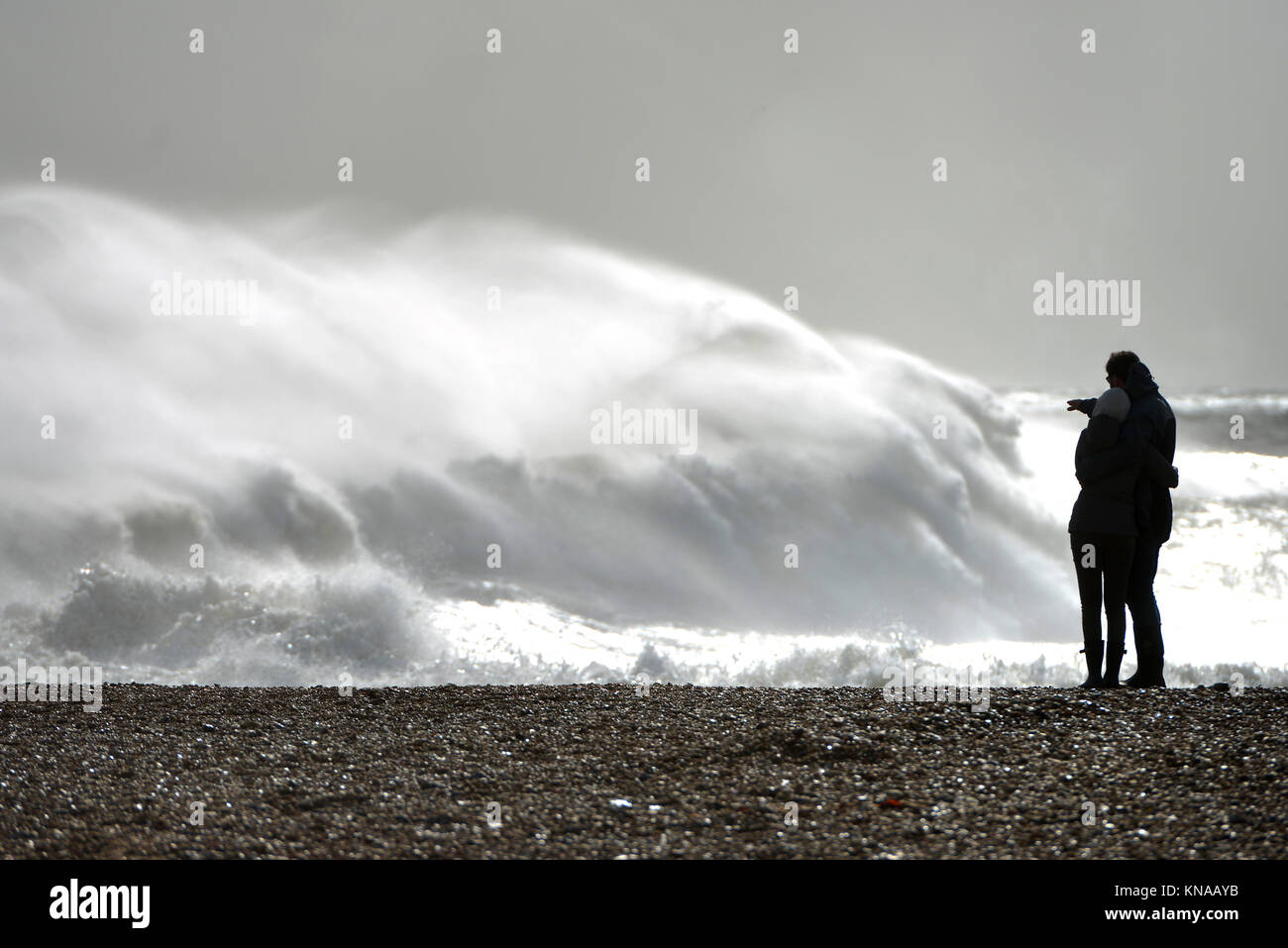 Giovane su una spiaggia a guardare un mare in tempesta Foto Stock