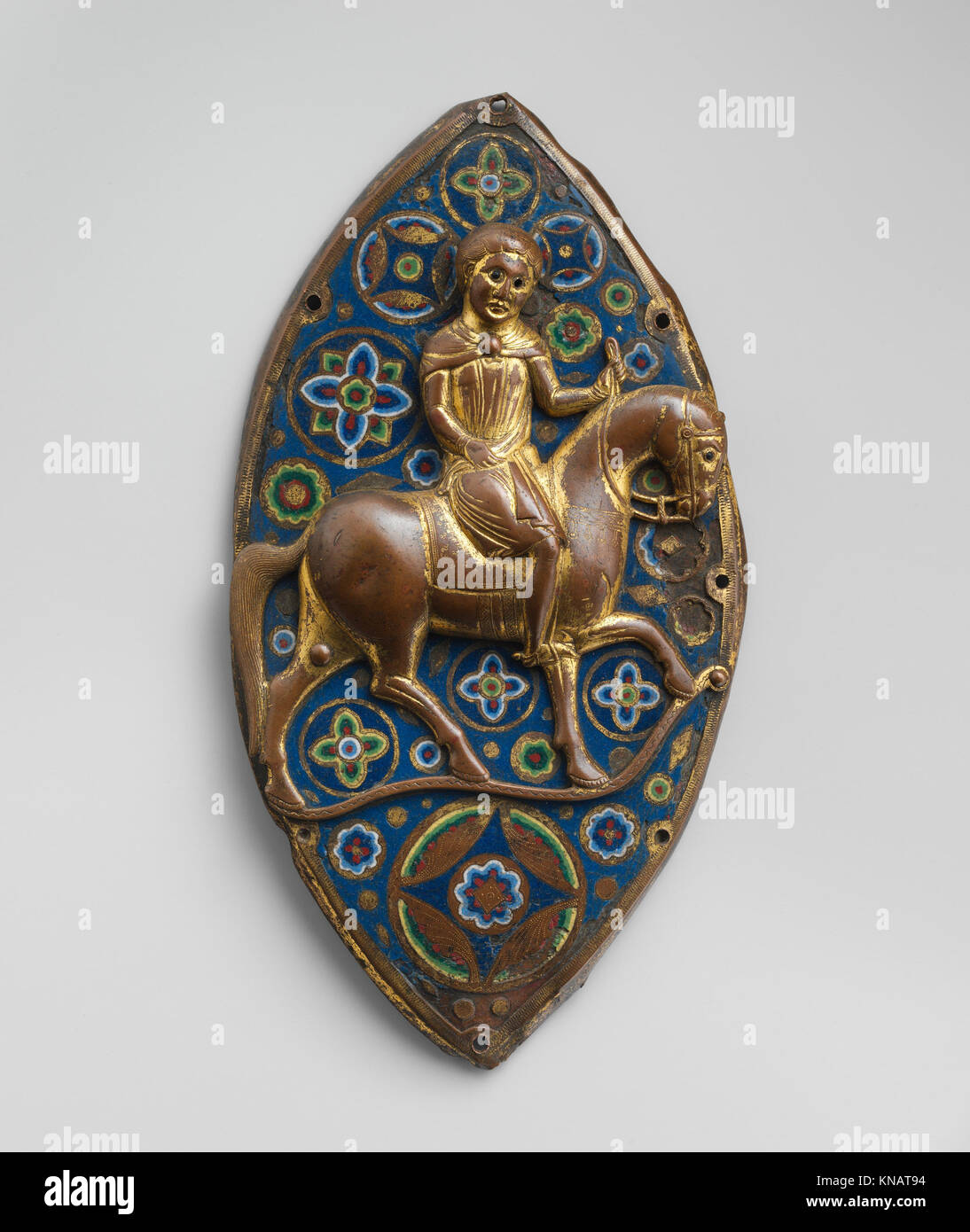 Questa placca equestre francese in rame del XIII secolo combina disegni incisi, stipati e dorati con repoussé e smalto champlevé, con perle di vetro colorate, che esemplificano l'artigianato medievale. Foto Stock