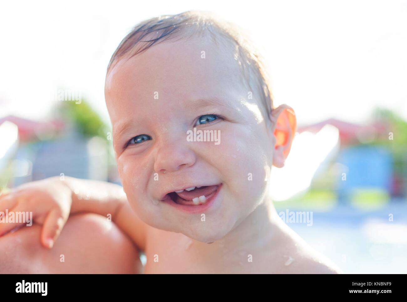 1 anno baby boy che mostra i suoi primi denti a swiming pool. Baby estate concetto. Foto Stock