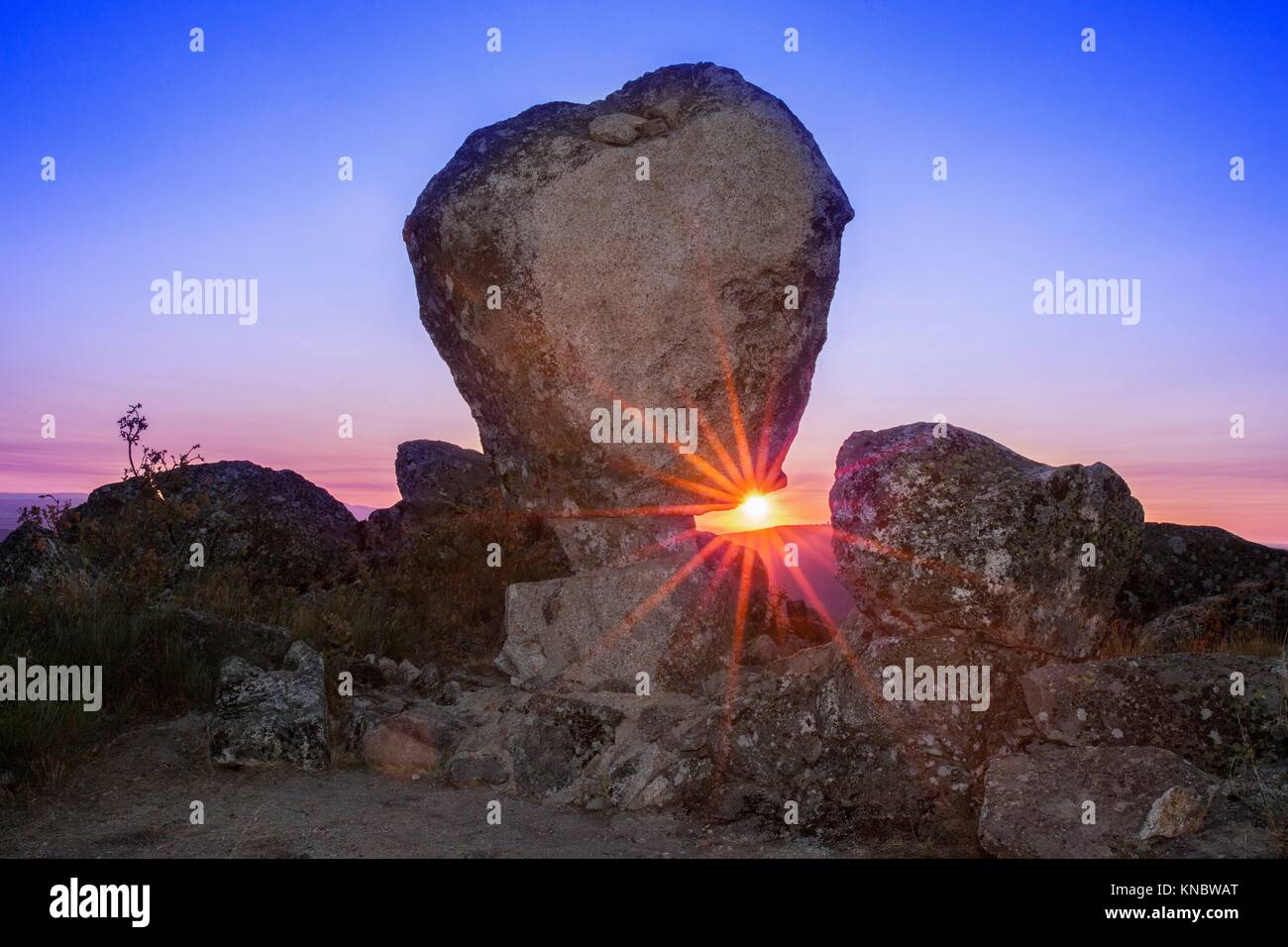 Il sorgere del sole tra il monumento megalitico di Cancho Que se Menea. In inglese il cambio rock. Montanchez, Spagna. Foto Stock