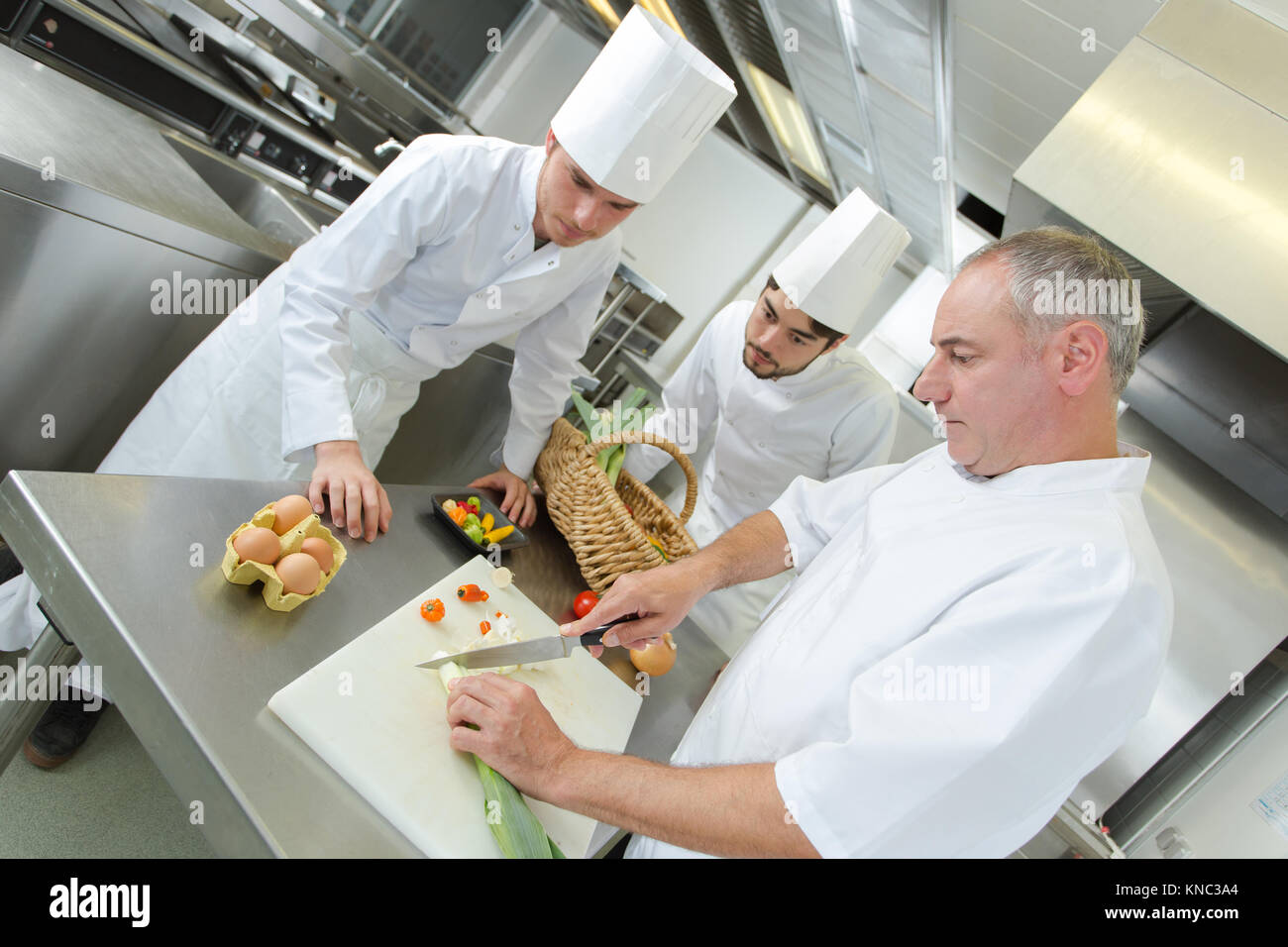 Il capo chef insegnamento i suoi assistenti nel ristorante cucina Foto Stock