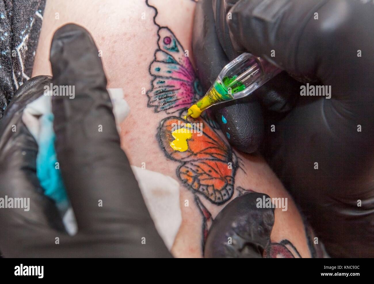 Tattoo Artist tattoo si applica al braccio. Ella è in fase di riempimento con il colore giallo del tatuaggio. Foto Stock