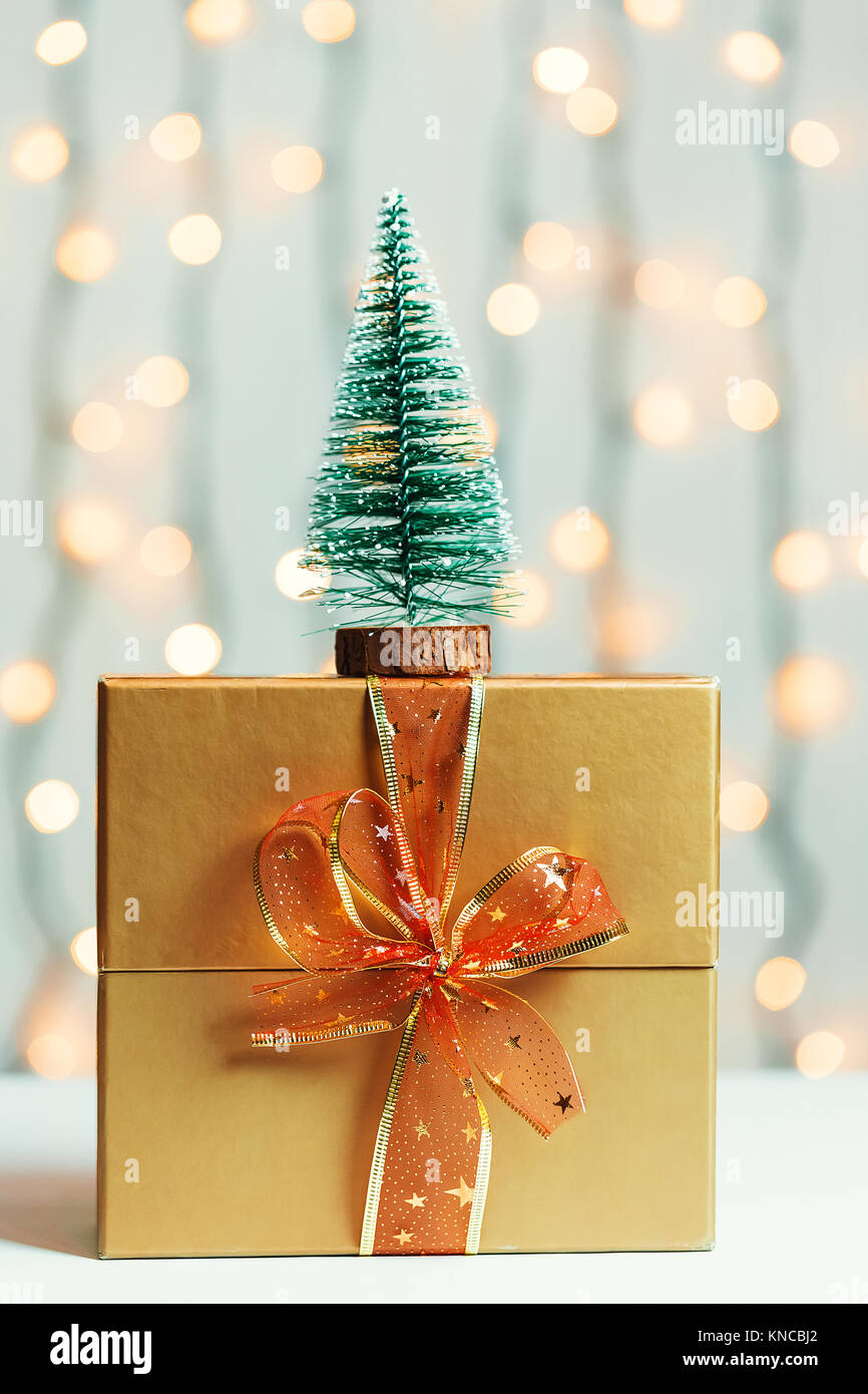 Un albero di Natale con confezione regalo su sfocato bokeh banner sullo sfondo di un luminoso garlandh e lavagne bianche. Buon Natale, idee per le cartoline per wi Foto Stock