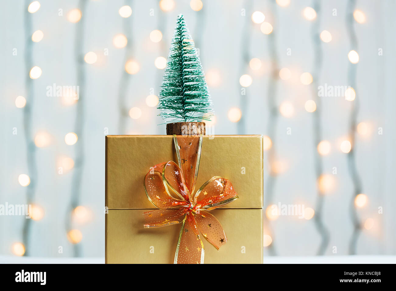 Un albero di Natale con confezione regalo su sfocato bokeh banner sullo sfondo di un luminoso garlandh e lavagne bianche. Buon Natale, idee per le cartoline per wi Foto Stock
