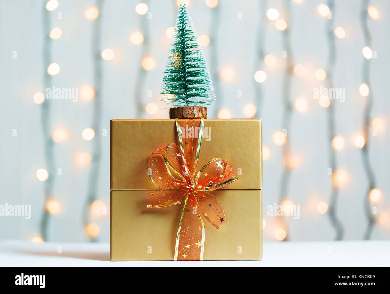 Un albero di Natale con confezione regalo su sfocato bokeh banner sullo sfondo di un luminoso garlandh e lavagne bianche. Buon Natale, idee per le cartoline per wi Foto Stock