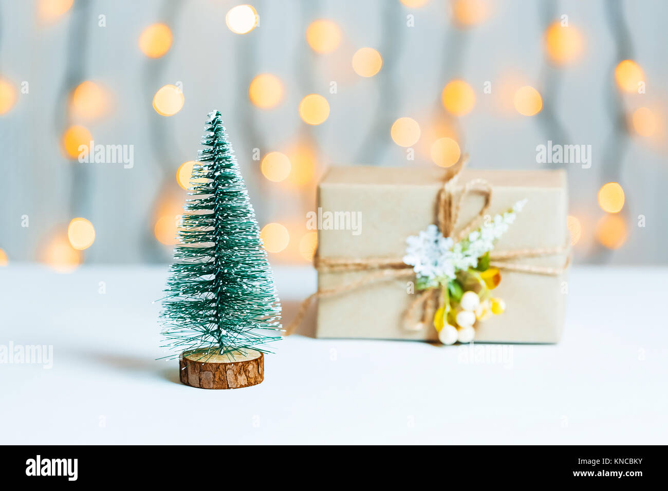 Un albero di Natale con confezione regalo su sfocato bokeh banner sullo sfondo di un luminoso garlandh e lavagne bianche. Buon Natale, idee per le cartoline per wi Foto Stock