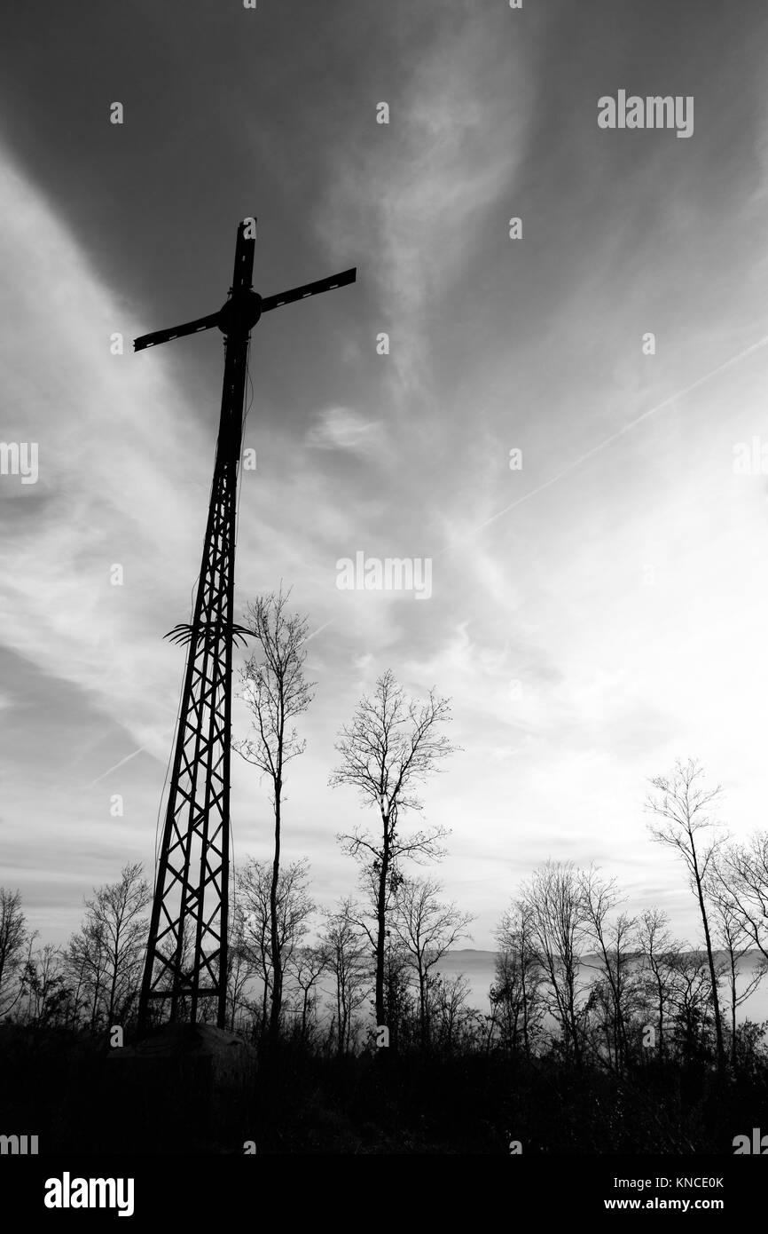 Un alto crocifisso di metallo con alberi e qualche nebbia all ora d'oro Foto Stock