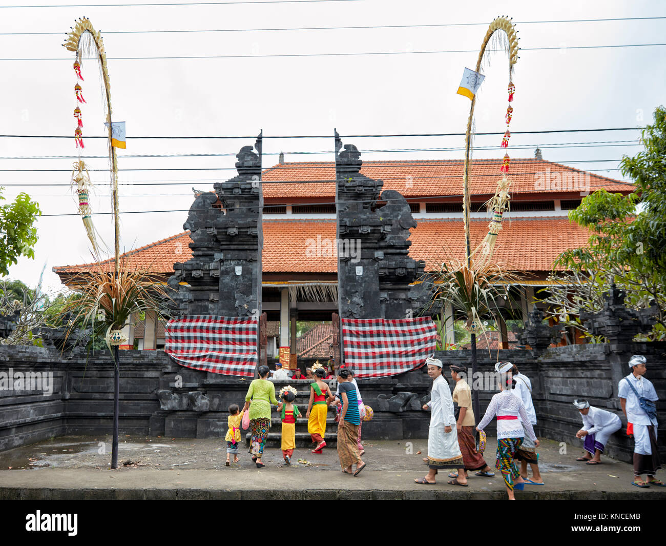 Persone che indossano il tradizionale design Balinese abbigliamento andare ad un locale il tempio vicino villaggio Bugbug. Karangasem Regency, Bali, Indonesia. Foto Stock