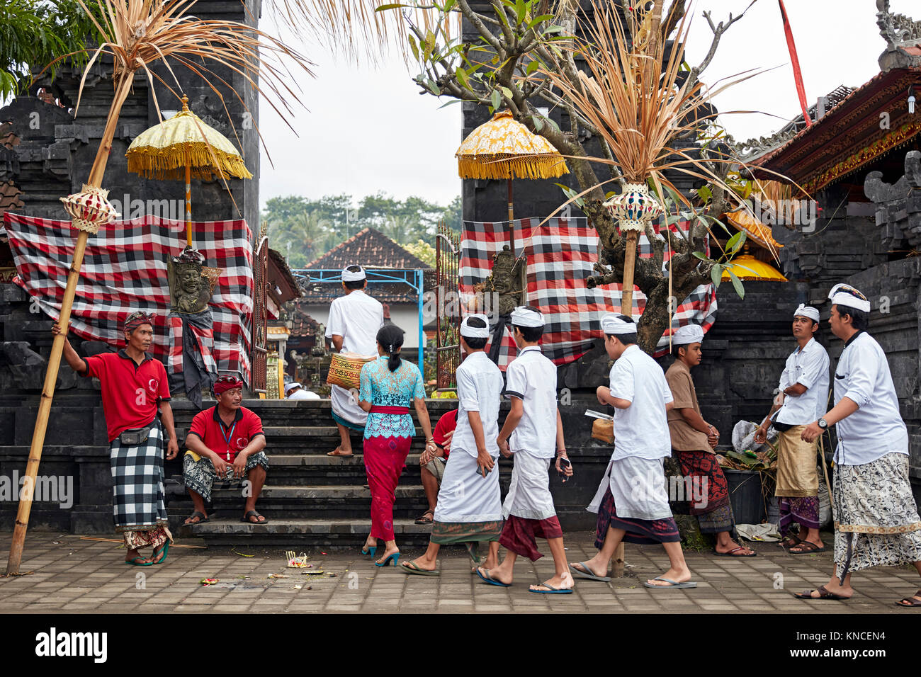 Persone che indossano il tradizionale design Balinese abbigliamento andare ad un locale il tempio vicino villaggio Bugbug. Karangasem Regency, Bali, Indonesia. Foto Stock