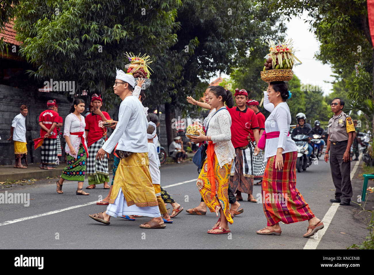 Persone che indossano il tradizionale design Balinese abbigliamento andare ad un locale il tempio vicino villaggio Bugbug. Karangasem Regency, Bali, Indonesia. Foto Stock
