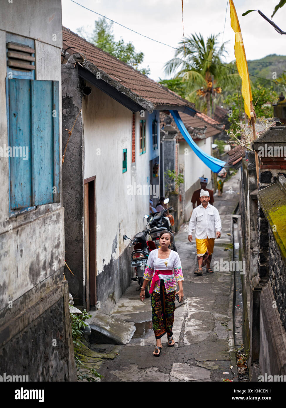 Persone che indossano il tradizionale design Balinese abbigliamento andare ad un locale il tempio vicino villaggio Bugbug. Karangasem Regency, Bali, Indonesia. Foto Stock