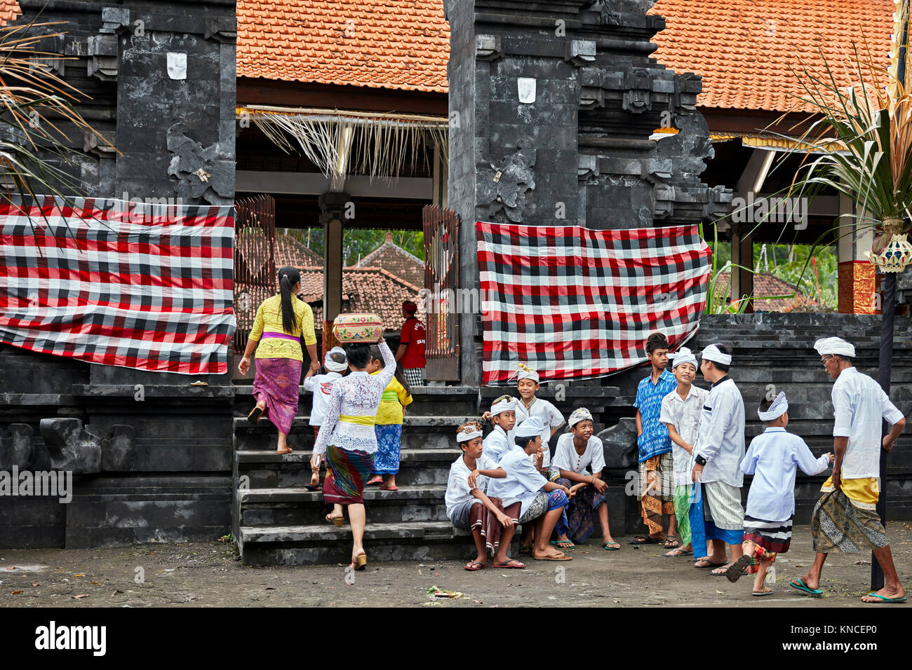 Persone che indossano il tradizionale design Balinese abbigliamento andare ad un locale il tempio vicino villaggio Bugbug. Karangasem Regency, Bali, Indonesia. Foto Stock