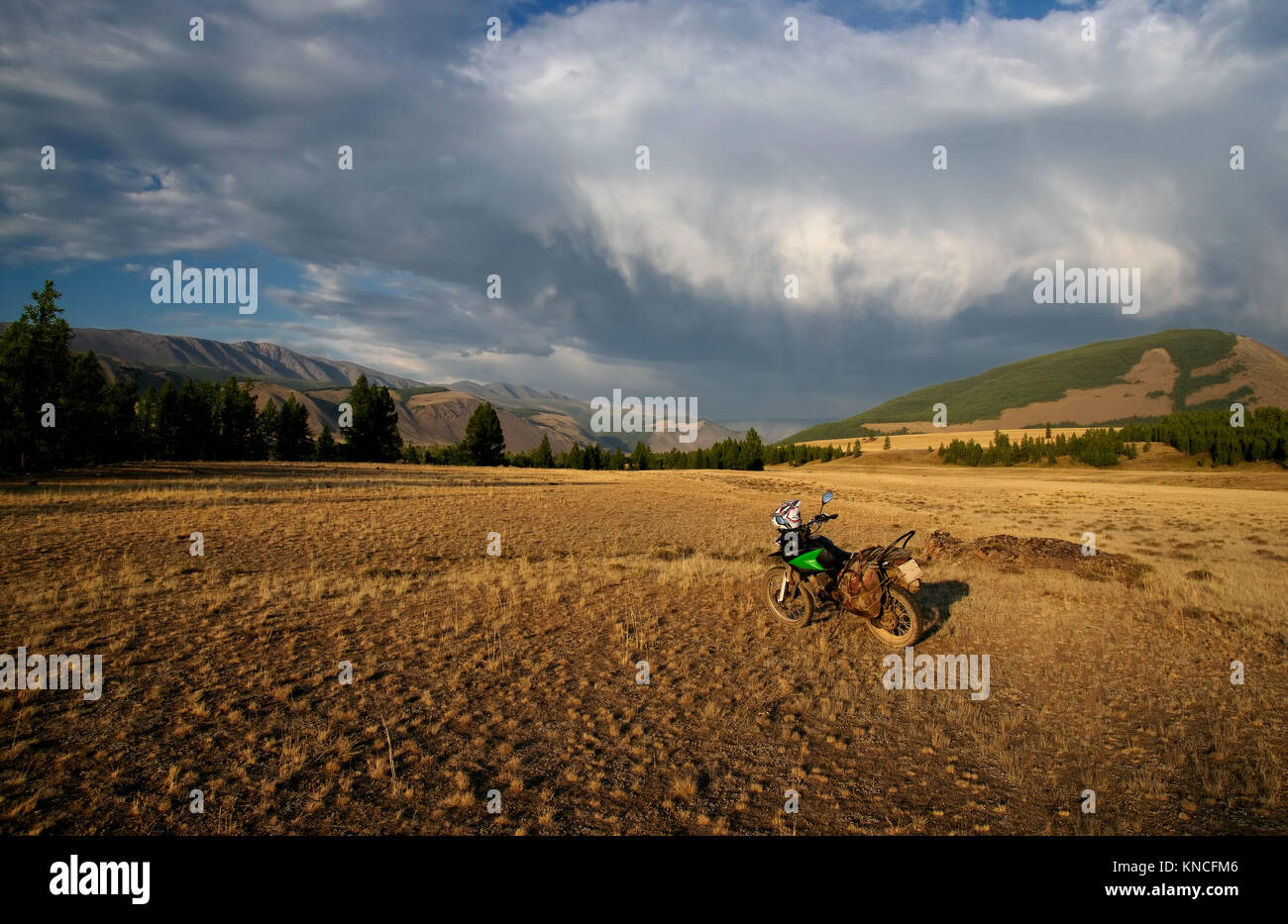 Moto Enduro da soli viaggiatori steppa il paesaggio sullo sfondo di alte montagne al tramonto sulle montagne di Altai in Siberia Russia Foto Stock