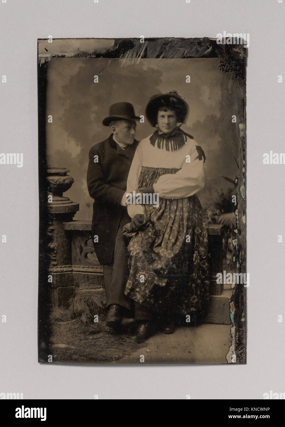 Questa opera raffigura due uomini, uno vestito con abbigliamento femminile, che si tengono per mano, esplorando temi di identità, espressione di genere e norme sociali all'interno del contesto storico. Foto Stock