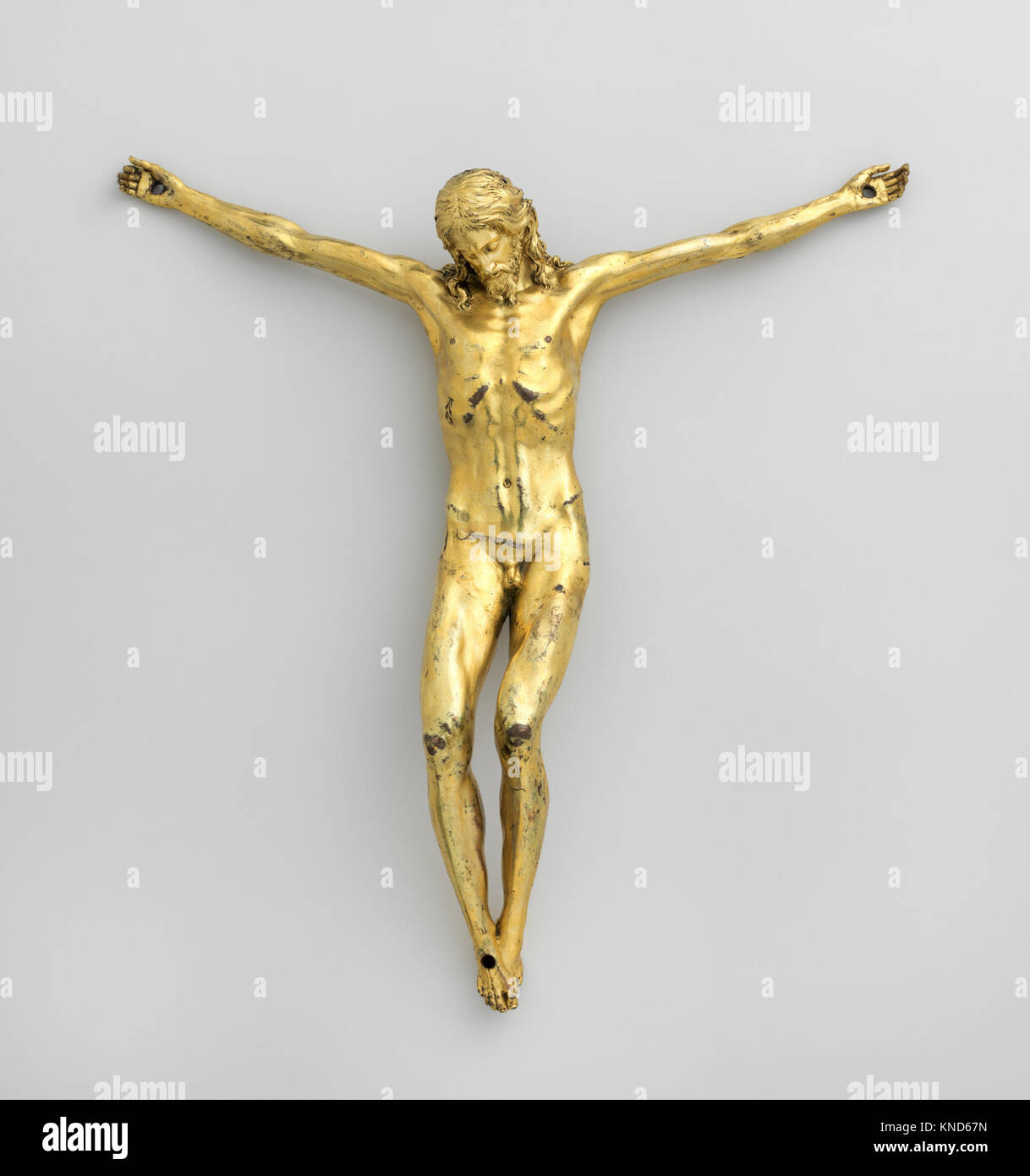 Crocifisso italiano dell'inizio del XVII secolo con una figura in bronzo dorato e argento su una moderna croce in legno, che mostra l'arte religiosa e l'artigianato dettagliato. Foto Stock