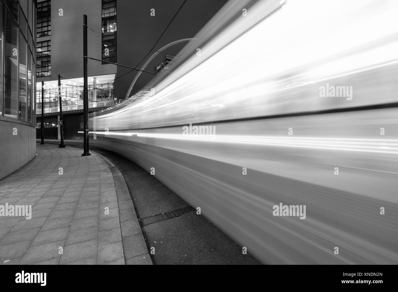 Il centro città di Manchester a notte con tram in movimento Foto Stock