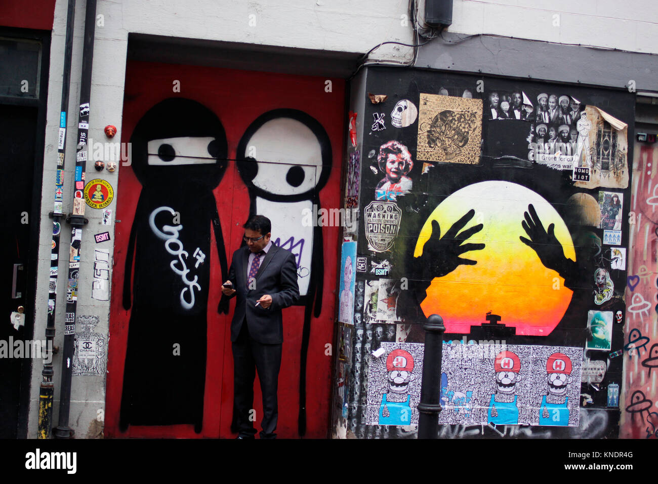 Uomo di fumare mentre utilizzando il suo telefono cellulare vicino a Brick Lane nella zona est di Londra Foto Stock