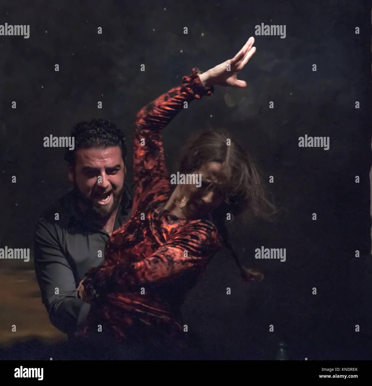 Appassionato di ballo flamenco. La Danzatrice con dishevelled capelli castani, sollevato la sua mano destra in condizioni di luce intensa. Il cantante dietro di lei. Foto Stock