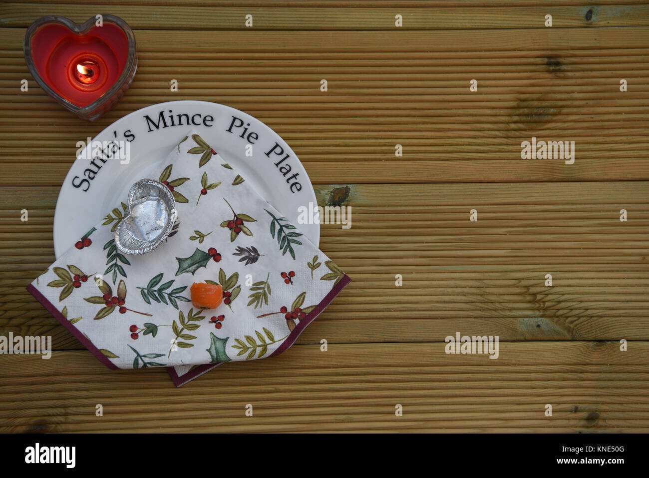 Natale tradizione di lasciare Santa Claus un trito torta e una carota per le renne vigilia di Natale su questa piastra con candele in legno rustico con spazio Foto Stock