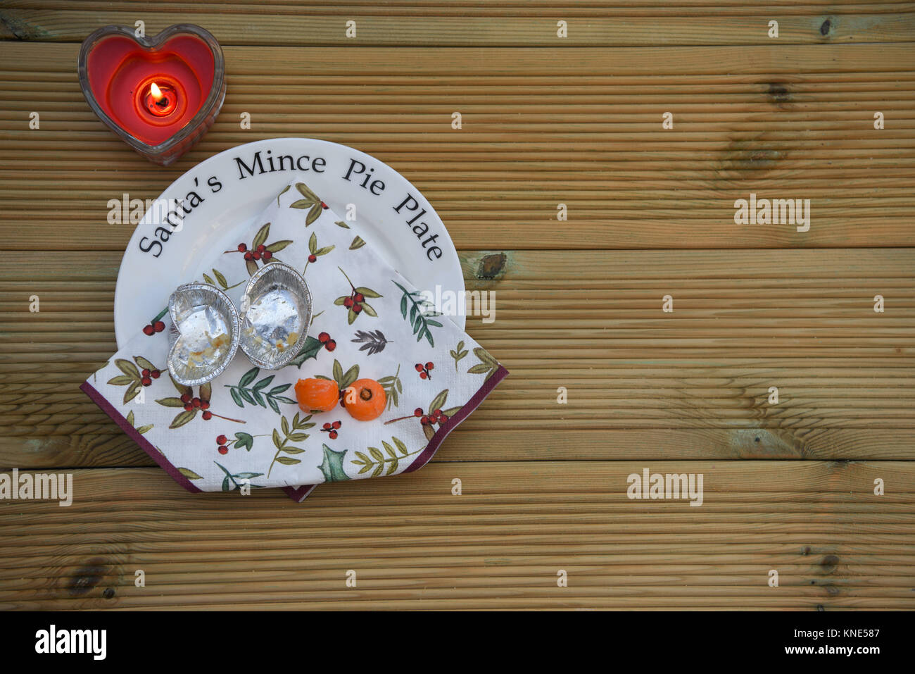 Natale tradizione di lasciare Santa Claus un trito torta e una carota per le renne vigilia di Natale su questa piastra con candele in legno rustico con spazio Foto Stock