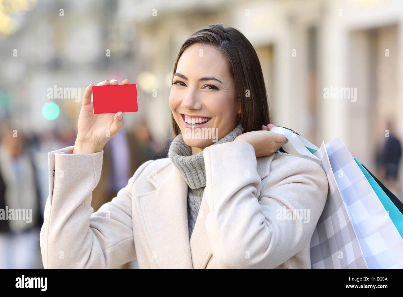 Ritratto di un cliente soddisfatto che mostra un fustellato carta di credito su strada in inverno Foto Stock