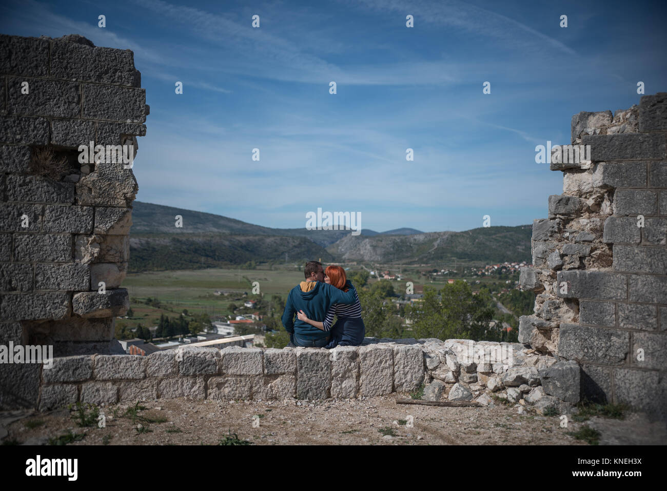 Coppia giovane seduto su una parete kissing, Stolac, Bosnia Foto Stock