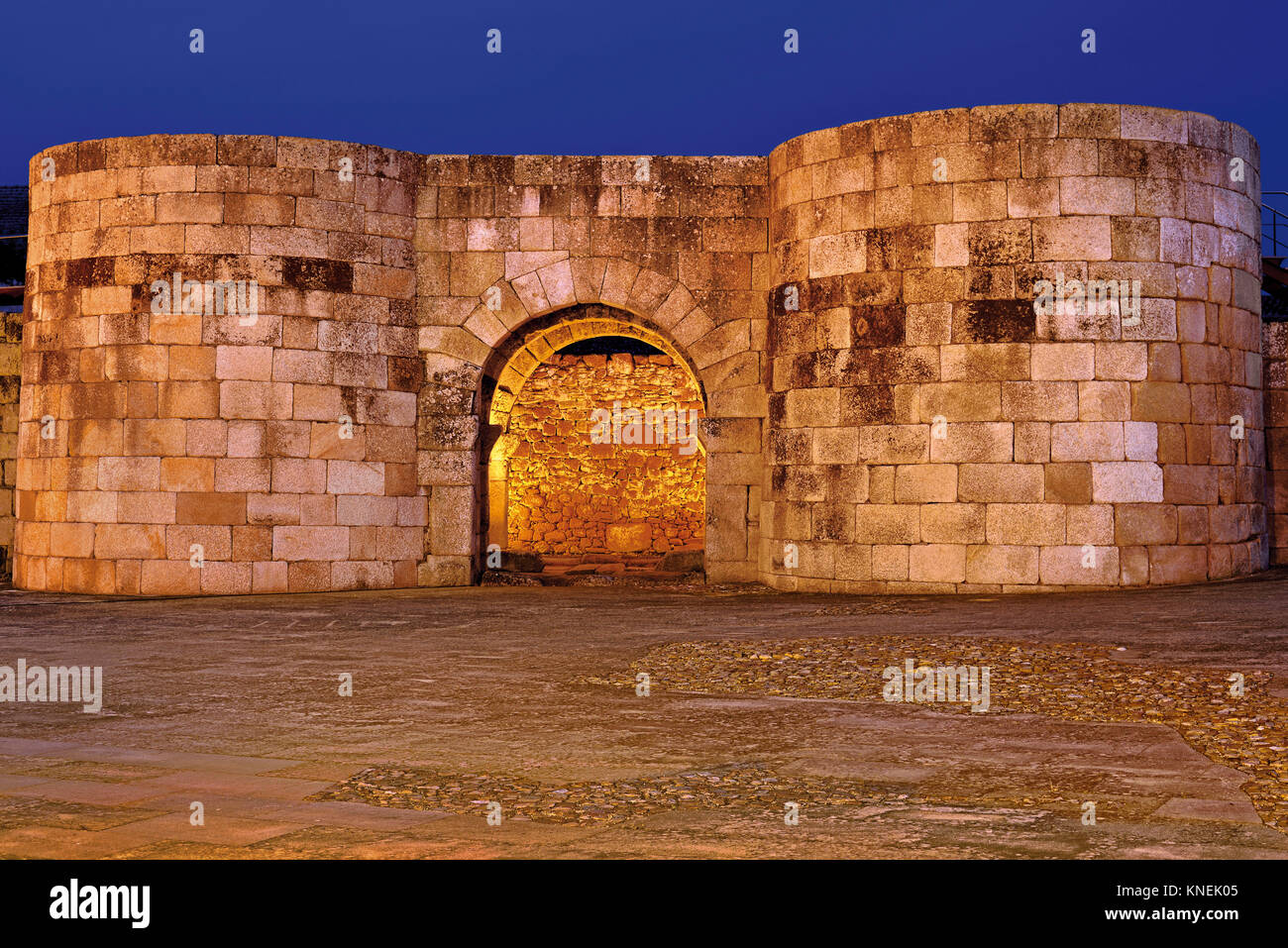 Orologio notturno illumina le mura romane e il gateway Porta Nova nel villaggio storico di Idanha-a-Velha Foto Stock