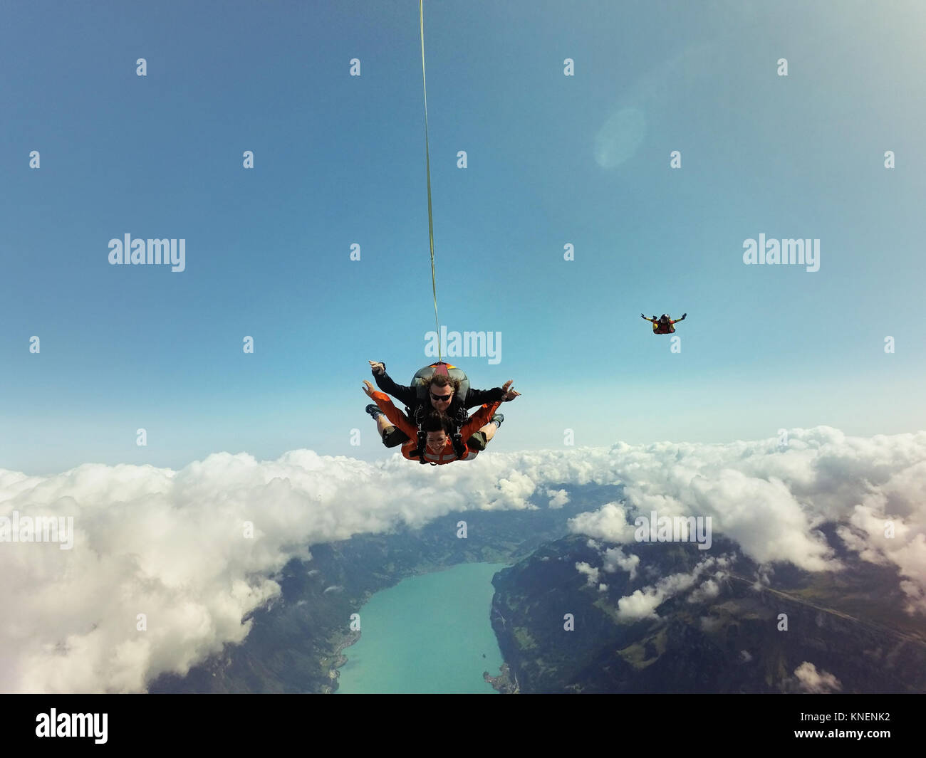 Ritratto di skydivers tandem al di sopra delle nuvole e del paesaggio Foto Stock