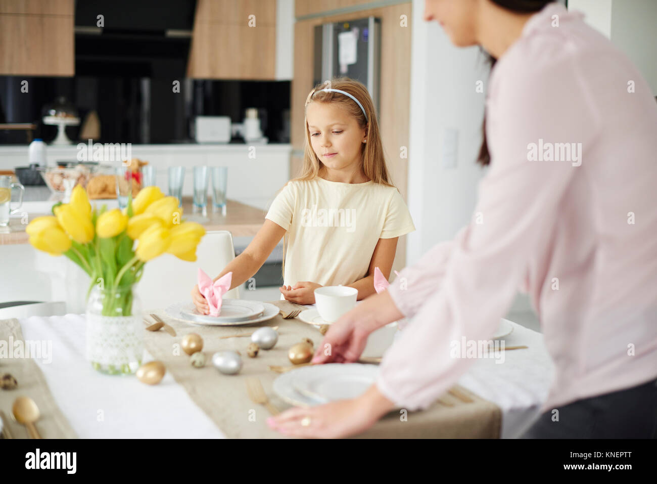 Ragazza madre e preparare le regolazioni del posto a pasqua tavolo da pranzo Foto Stock