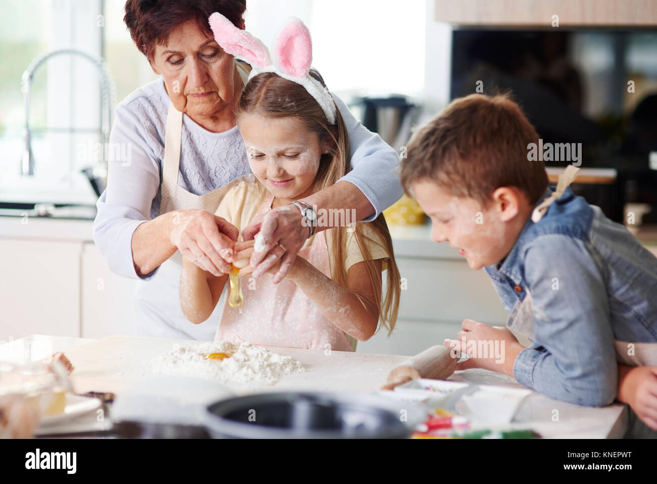 Nonna aiutando la ragazza a pasqua cuocere a banco di cucina Foto Stock