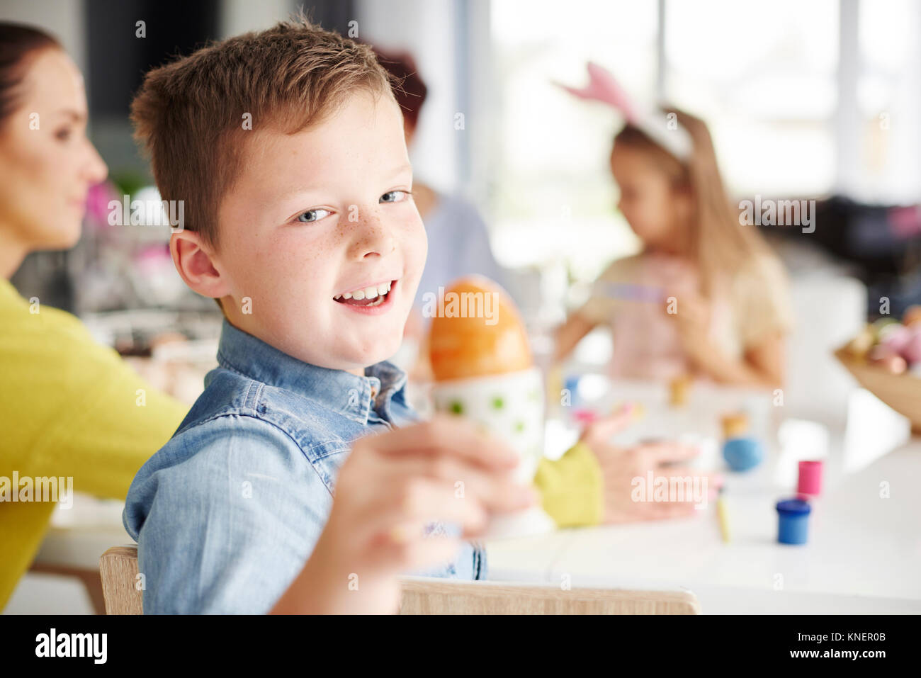 Ritratto di ragazzo holding dipinto sode uovo di pasqua a tavola Foto Stock