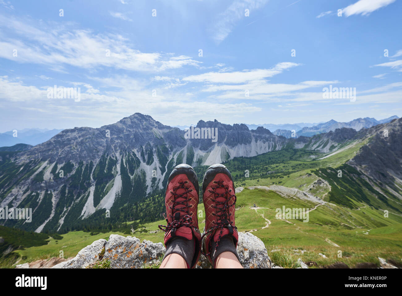 Punto di vista personale femminile di escursionista scarponcini da trekking al di sopra della Valle di Tannheim montagne, Tirolo, Austria Foto Stock