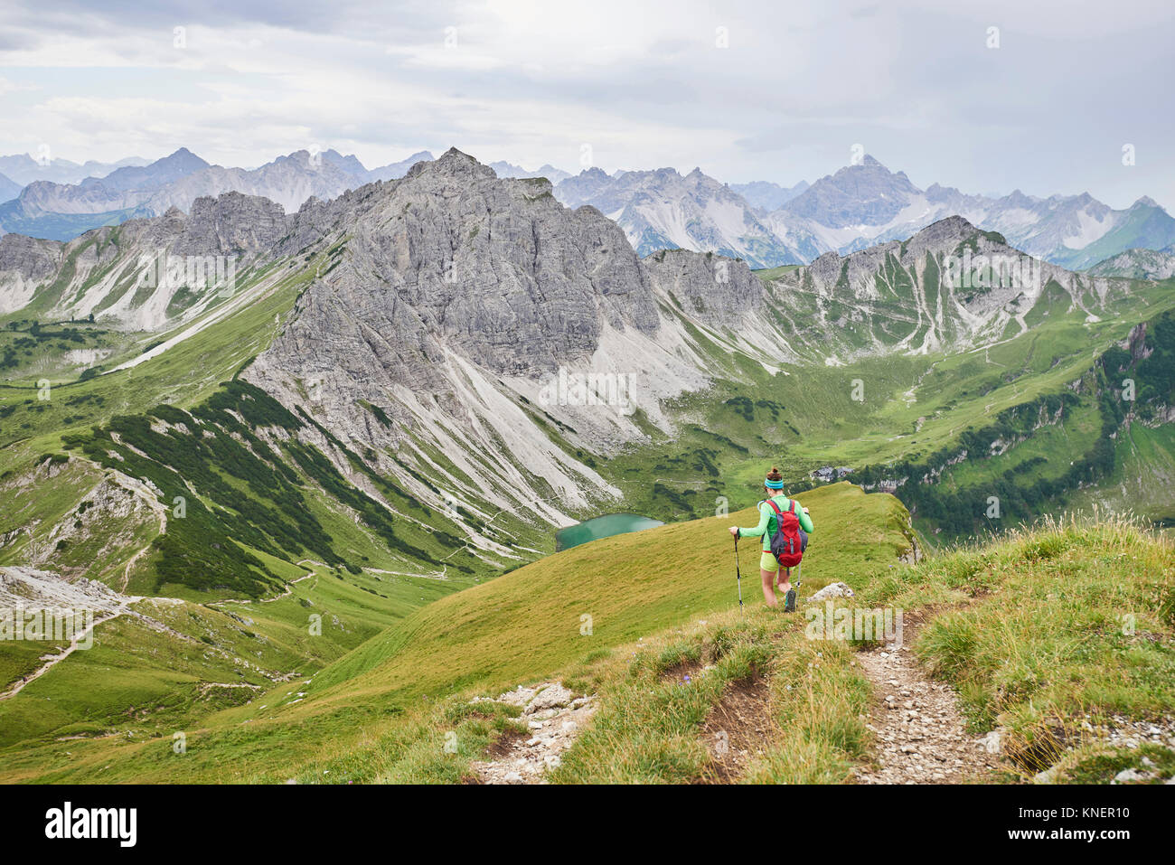 Vista posteriore di un escursionista femmina escursionismo giù nella Valle di Tannheim montagne, Tirolo, Austria Foto Stock