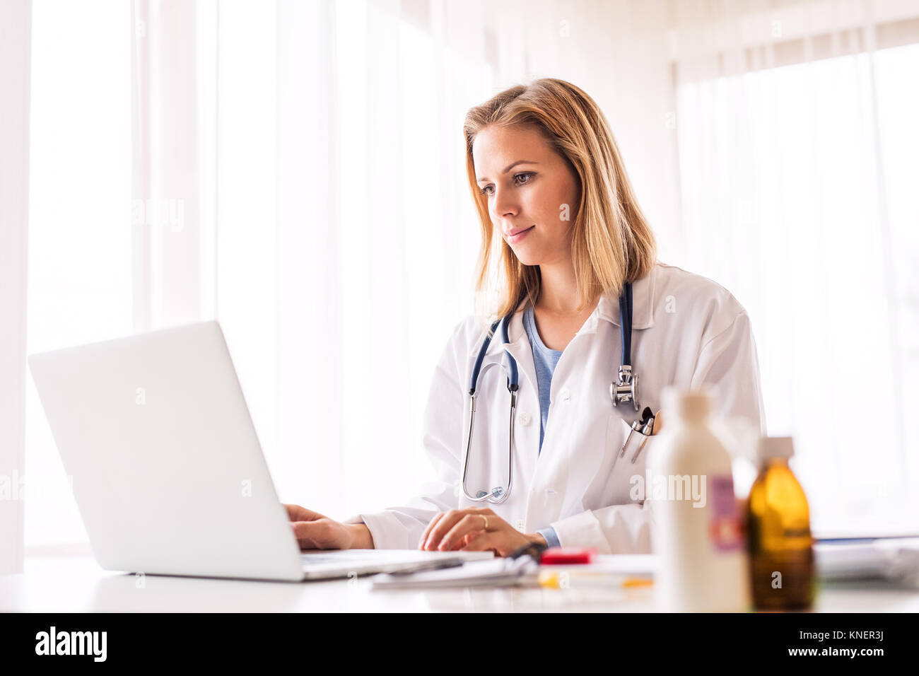 Medico donna con laptop lavorare alla scrivania in ufficio. Foto Stock