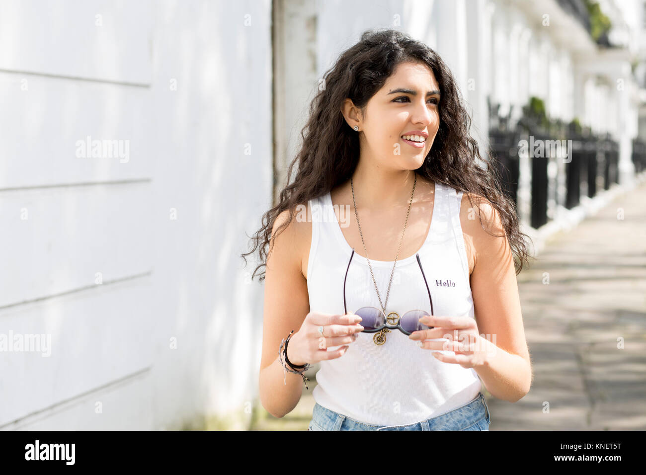 Giovane donna con lunghi capelli ondulati per passeggiare sulla tenuta di strada occhiali da sole Foto Stock
