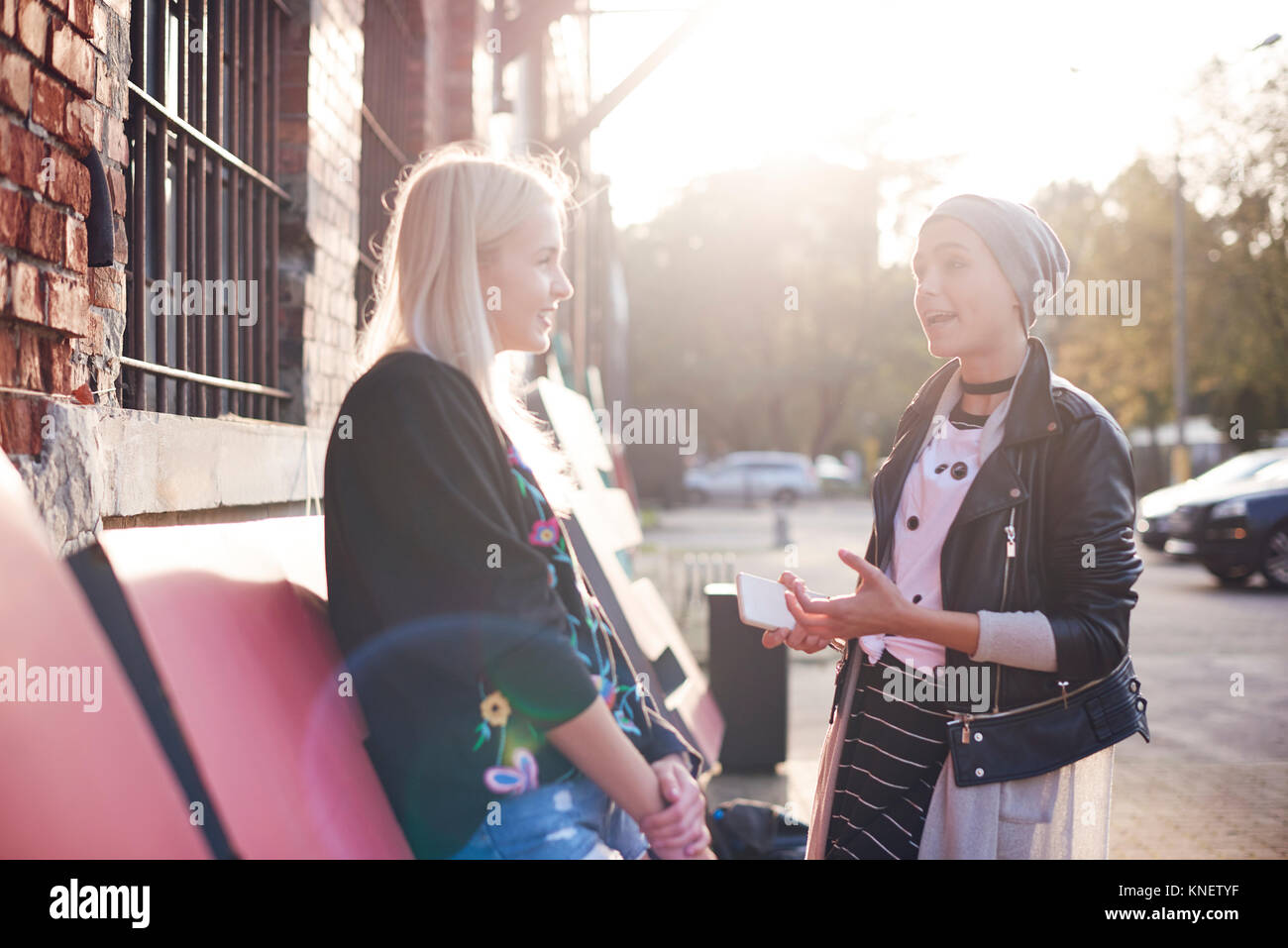 Due giovani amici di sesso femminile in chat sul soleggiato strada di città Foto Stock